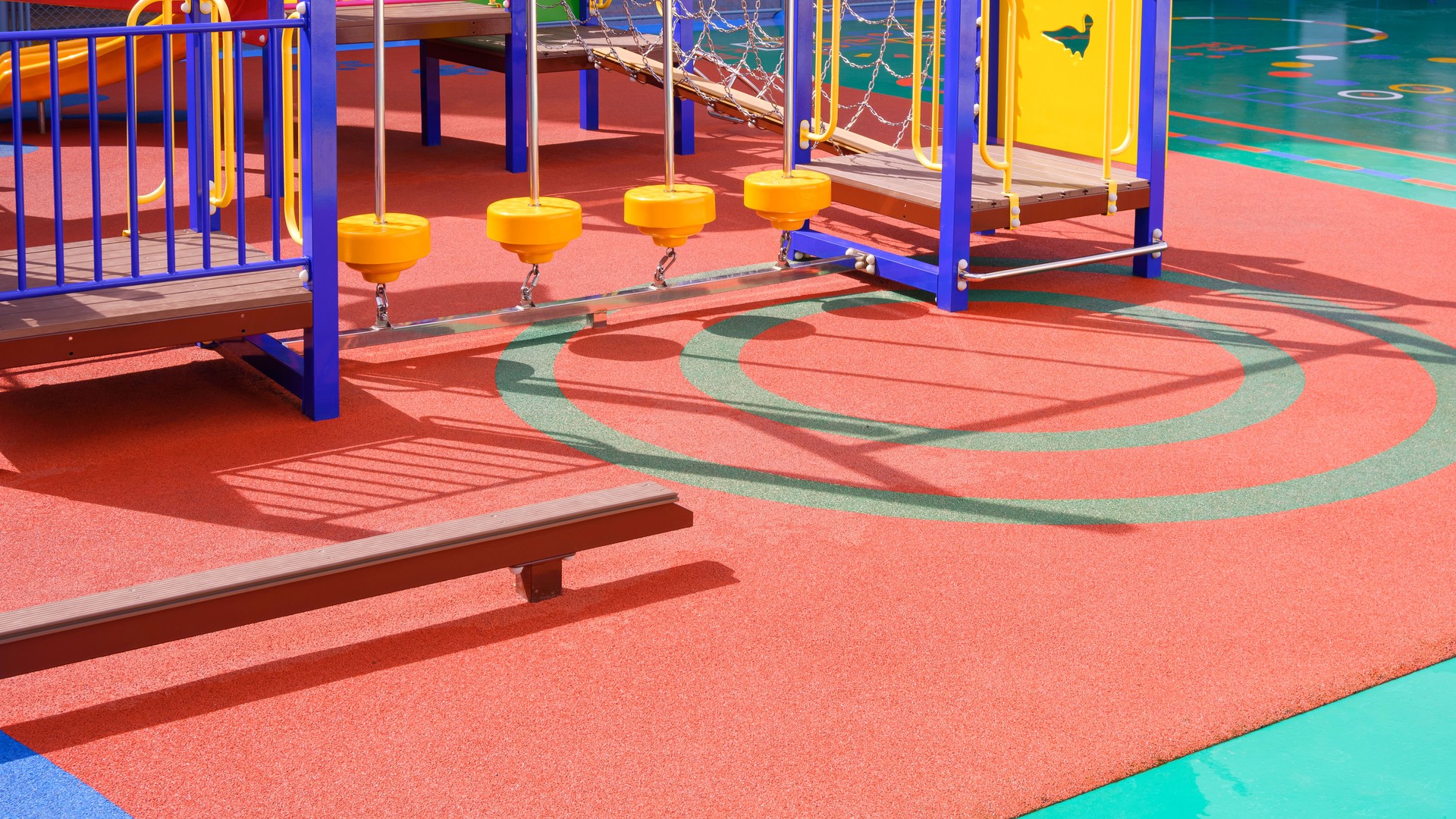 Playground climbing equipment with balance beams on colorful rubber floor in outdoors playground area at kindergarten