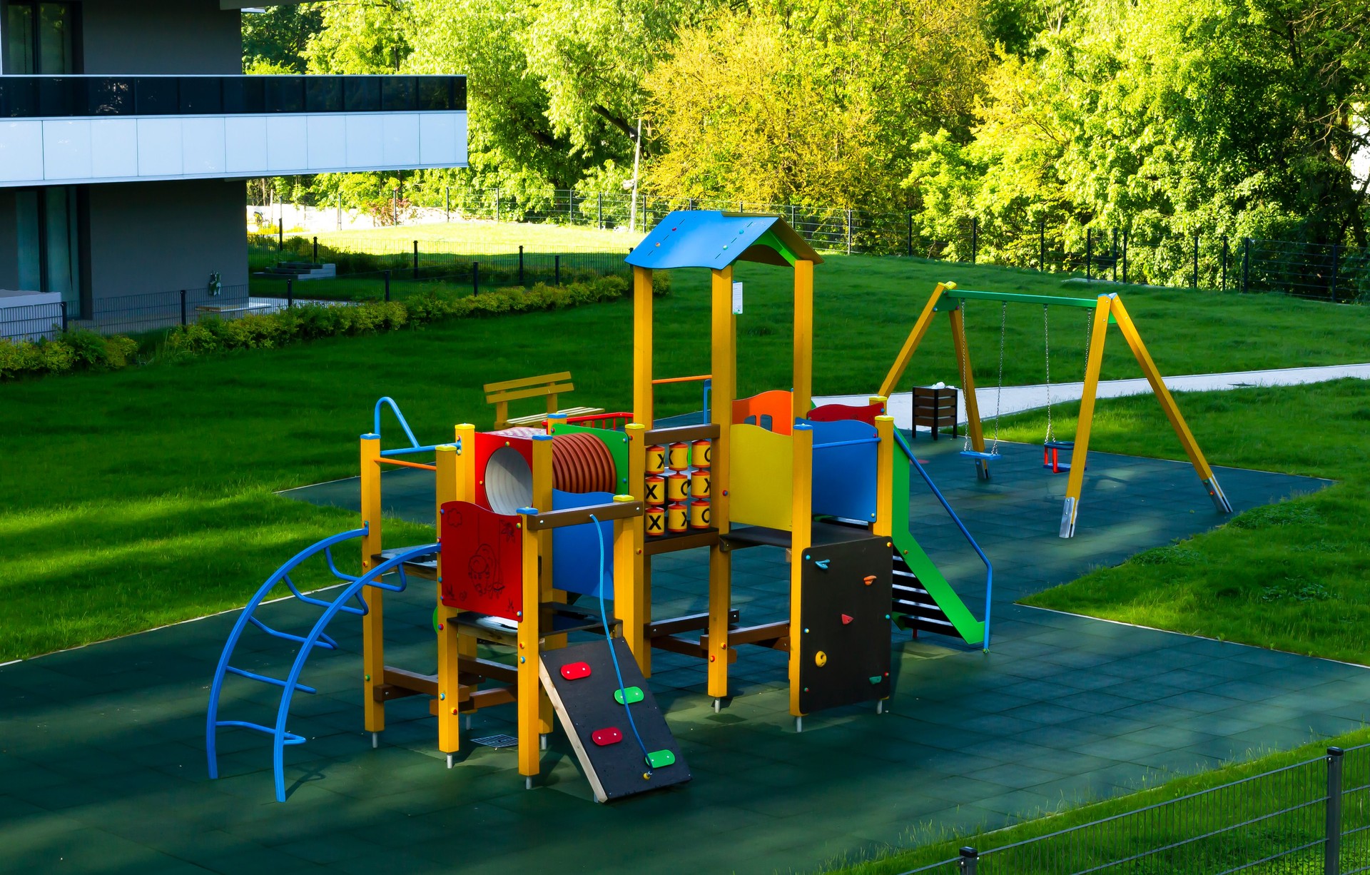 Eco-friendly modern colorful wooden children (kids) playground (play yard, playset) with beautiful lawn in a new residential complex (campus), without children, in the green park area. Horizontal.